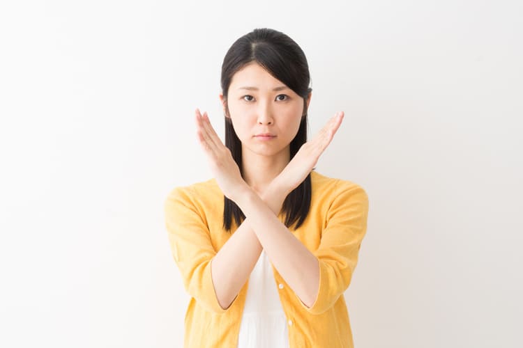 バツ印をしている女性